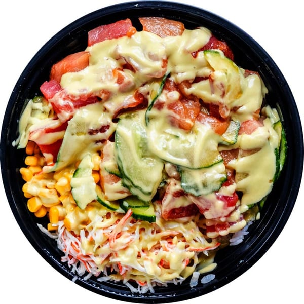 A colorful poke bowl with tuna, zucchini, corn, and crab salad, drizzled with sauce.